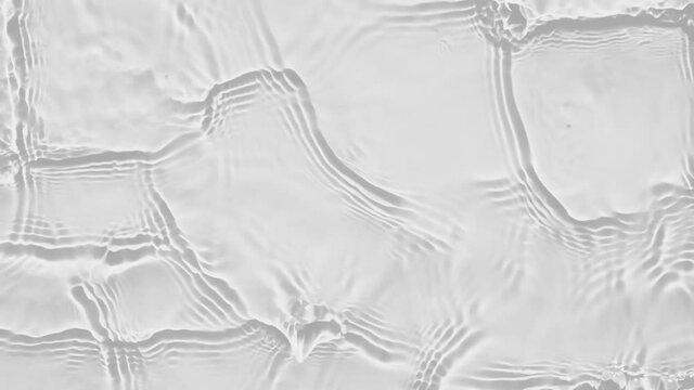 Up close, top view, Slow motion various waves of the water surface hitting the sun's rays, making them sparkle according to different patterns on a gray background video 4K.