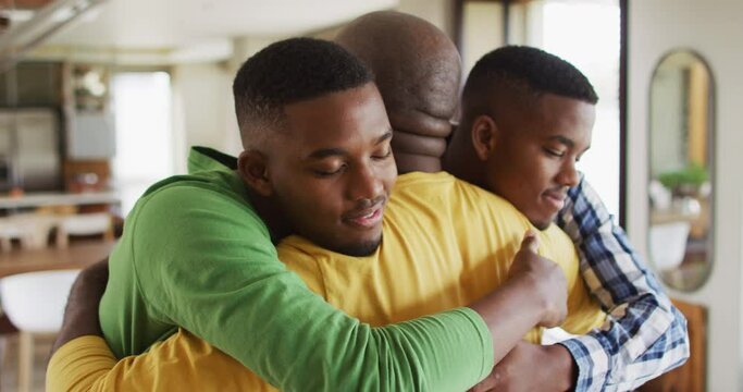 African american father embracing his twin teenage sons and smiling