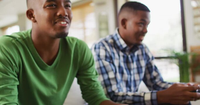Two african american brothers sitting on a couch and playing video games