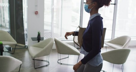 Diverse male and female business colleagues in face masks greeting touching elbows in office - Powered by Adobe