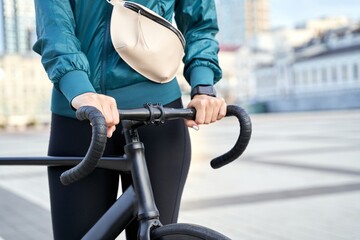 Woman in a sports jacket and leggings with a bicycle in the city