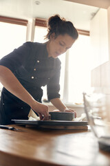 Fototapeta na wymiar young professional female cook is preparing tasty cake at her light modern kitchen