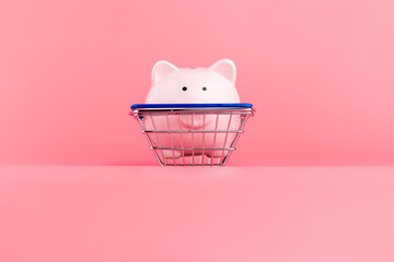 Pink piggy Bank with a shopping cart stands on a pink background. Online business shopping concept