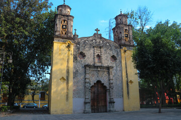 Naklejka premium fachada de iglesia católica entre árboles y cielo azul