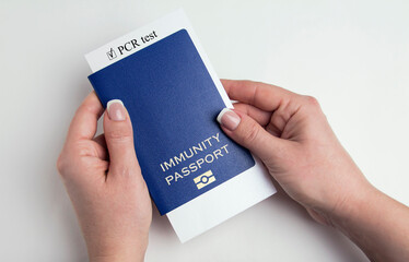 Blue passport in female hands. Human immunity passport on a white background.
