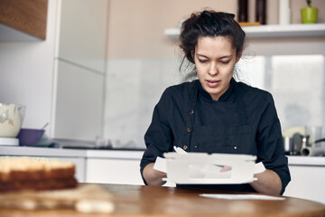 young professional female cook is preparing tasty cake at her light modern kitchen