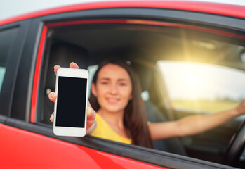 Woman in car shows smartphone with blank screen.