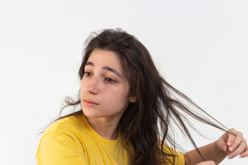 Woman with yellow t-shirt on white background passing cream on hair