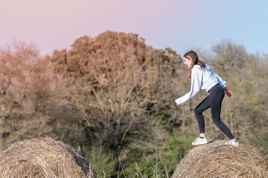 Latina Teenage Girl Posing On Top Of Straw Bales In Rural Setting, Lifestyle