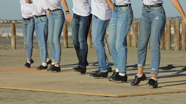 A group of people are dancing the Irish step outdoors. Popularization of Irish dances.
