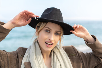Portrait of a stylish young woman wearing a beautiful hat on the beach 