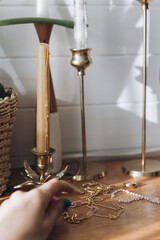 Modern gold and pearl accessories and blurred female hand on table with vintage candlesticks