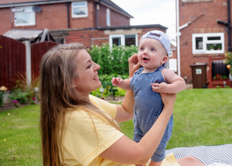 happy mother holding child in the garden in summer