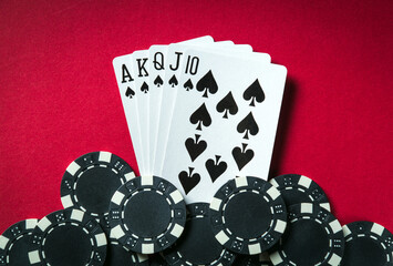 Obraz premium A winning poker combination is Royal Flush. Chips and cards on the red table in the poker club. Luck or Fortune