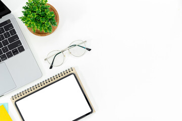 Top view of a desk with a laptop, tablet, notebooks, pot-it, and glasses  isolated on white background