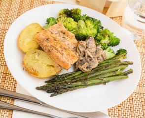 delicious dish of fried river trout fillet with garnish of broccoli, asparagus sprouts, baked potatoes and mushroom sauce