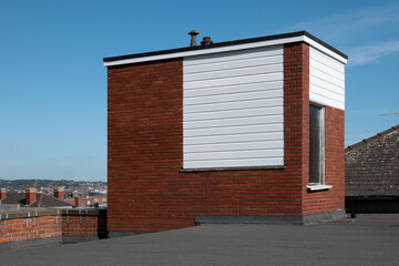 A traction elevator machine room on top of the lift shaft on a flat roof housing the motor, gears and machinery