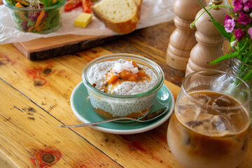 Breakfast rice pudding porridge with jam on a rustic wooden table in a cafe. 