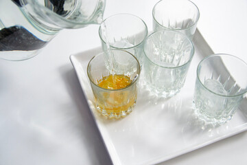 Water being poured into bright crystal glasses. Bright, white background 