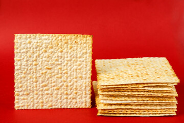 Matzo plates laid on top of each other on a red background next to the plate. copy space.
