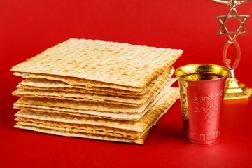 Matzah on a red background and a glass of wine for kiddush m menorah.