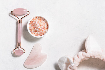Asian Gua Sha massage tools, sea salt and hair band on white marble background with copy space for your text. Skin care concept.