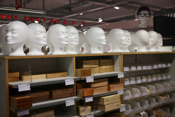 Many clay, plastic human heads for fashion modelling purposes on shelf.  White woman busts in a shop. 