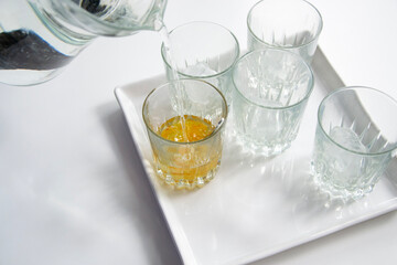 Water being poured into bright crystal glasses. Bright, white background 