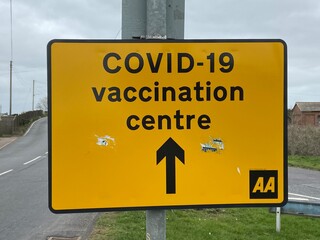 Covid-19 Vaccination Centre, New Romney, East Sussex, UK - 03.03.2021: Yellow road sign directing to  Covid-19 Vaccination centre.