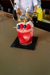 Rose Alcohol Cocktail with Berries raspberry, blueberry and ice in bar. Blurred background