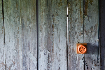 old wooden wall door with a bright orange electrical socket