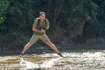A young man dancing on the water on a sunny day, on a mountain river. © NAIL BATTALOV
