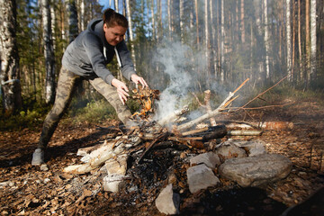 Girl lights a fire for cooking in the spring forest