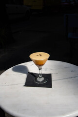 Espresso coffee cocktail served on a wood table in a martini glass. Black background