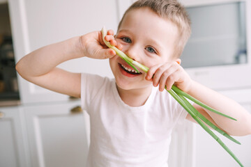 Cute boy preparing a salad of fresh vegetables. Boy preparing a salad for his mother