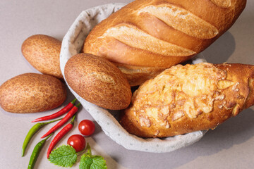 Fresh bread in a basket on the table with red peppers and tomatoes.
