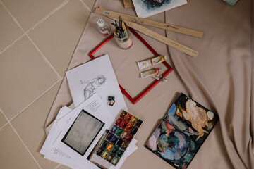 artist's workshop with brushes, paints, drawings and picture frames