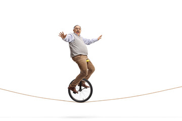 Full length profile shot of an excited mature man riding a mono-cycle on a rope © Ljupco Smokovski