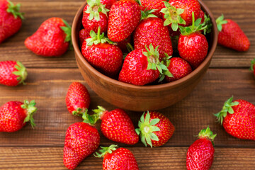 Fresh juicy organic strawberries in a clay bowl. Ripe red strawberries in a bowl on a wooden background