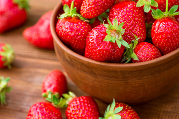 Fresh juicy organic strawberries in a clay bowl. Ripe red strawberries in a bowl on a wooden background