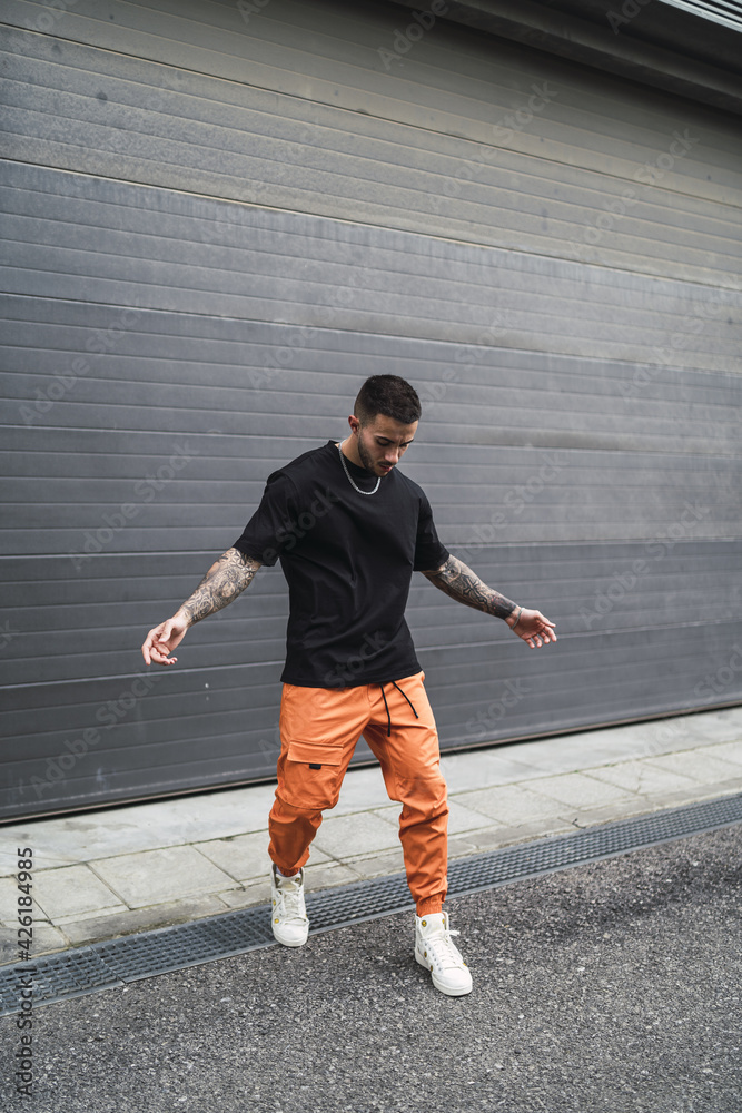 Wall mural spanish stylish man with tattoos posing in the street