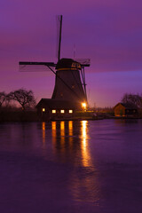 Fototapeta na wymiar Windmills at sunset in Kinderdijk near Rotterdam in The Netherlands during winter with ice on canal