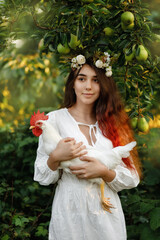 a girl in a white dress is holding a beautiful white rooster 