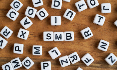 Tiny white and black bead cubes on wooden board, letters in middle spell SMB for Small to medium business