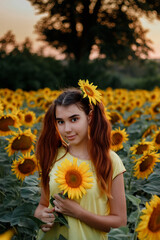 beautiful redhead girl in a yellow t-shirt on a field with sunflowers at sunset