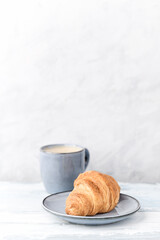 Croissant with coffee on bright wooden background. Copy space.	