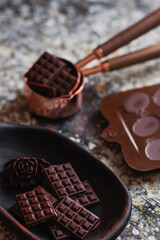 Assortment of different chocolate types in wooden carved plate, with vintage props on the background