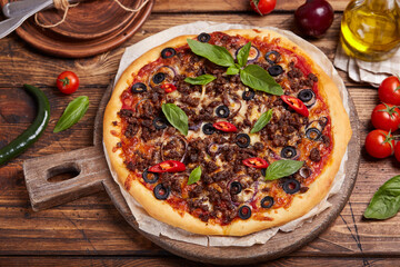 Beef barbeque Pizza with minced meat, red onion, chili pepper, black olives and mozzarella cheese. American style homemade pizza. Freshly baked and served with basil leafs.