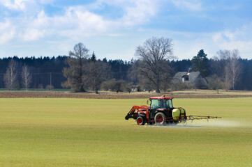 The tractor is watering the plants in the field. Agriculture