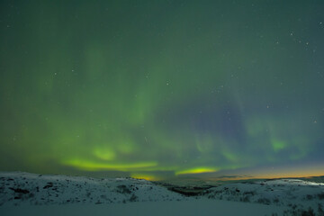 Northern lights in the sky. Snowy tundra at night.